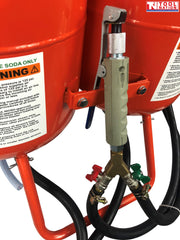 Close-up of the blasting gun handle mounted between the two tanks, with red and green control valves and black hoses connected below.