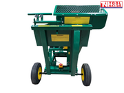 Rear view of a green towable saw bench showing two wheels, mesh guard, warning labels, frame and red emergency stop button.