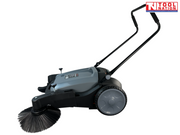 Side view of a grey and black manual sweeper with one round side brush, rear wheel, grey top cover and upright handle.