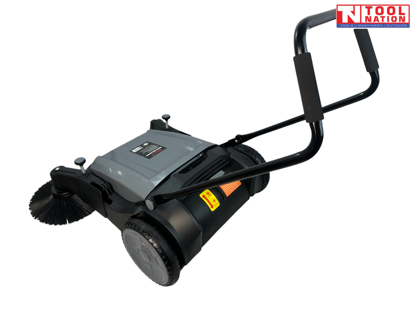 Rear side view of a grey and black manual sweeper with one round side brush, rear wheel, upright handle and warning labels.
