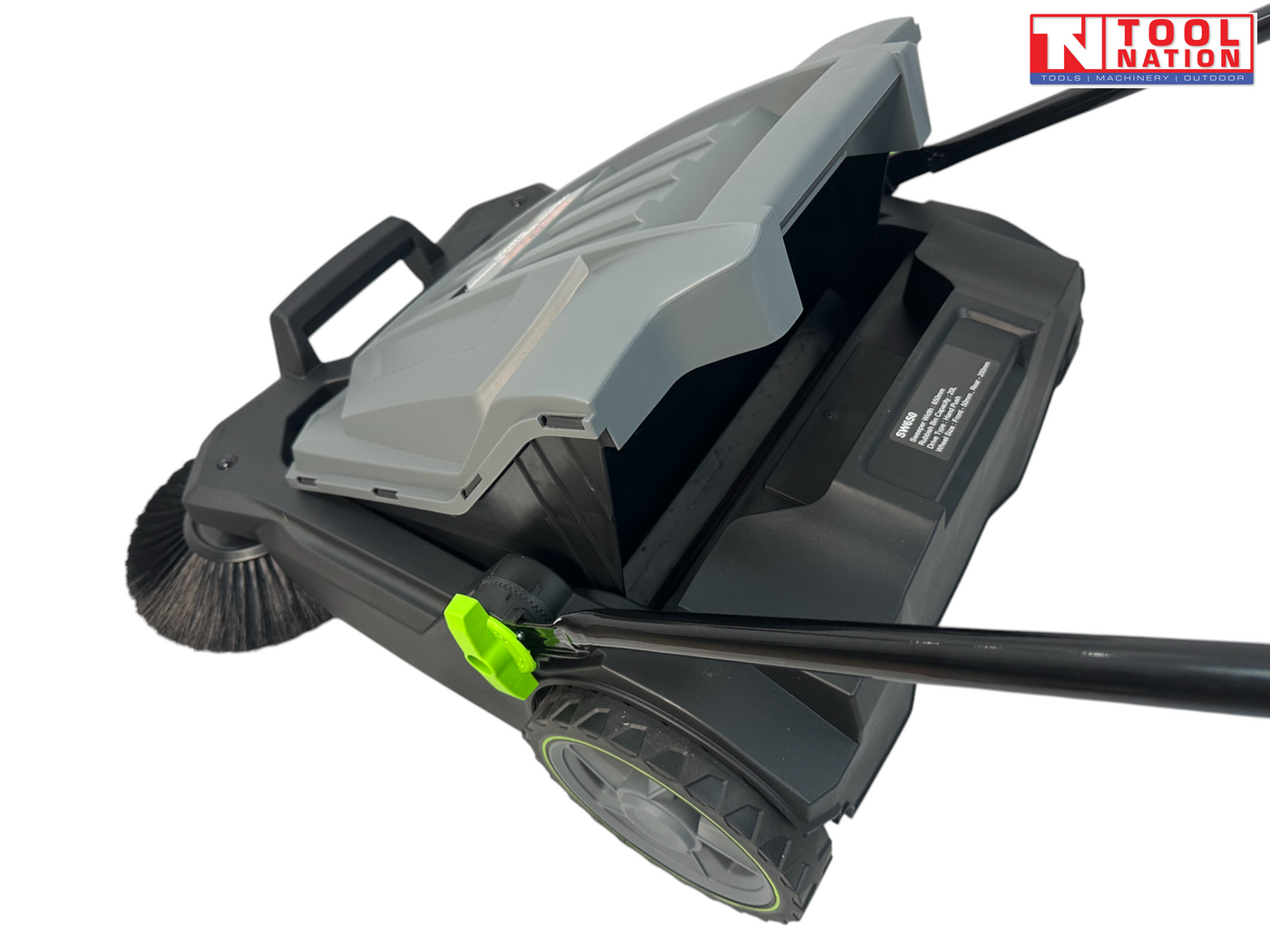 Close-up of a grey and black manual sweeper with the collection bin lifted, showing side wheel, round brush, handle rod and green adjustment knob.