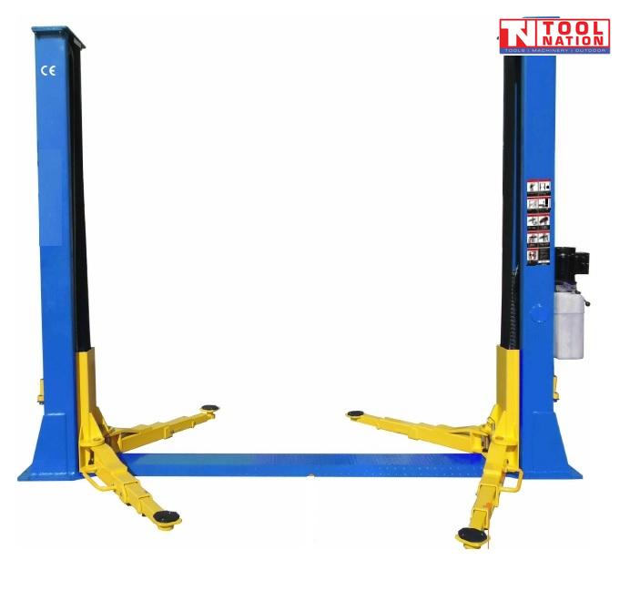 Angled view of a blue two-post vehicle lift with yellow lifting arms and a black floor plate between the posts on a light grey background.