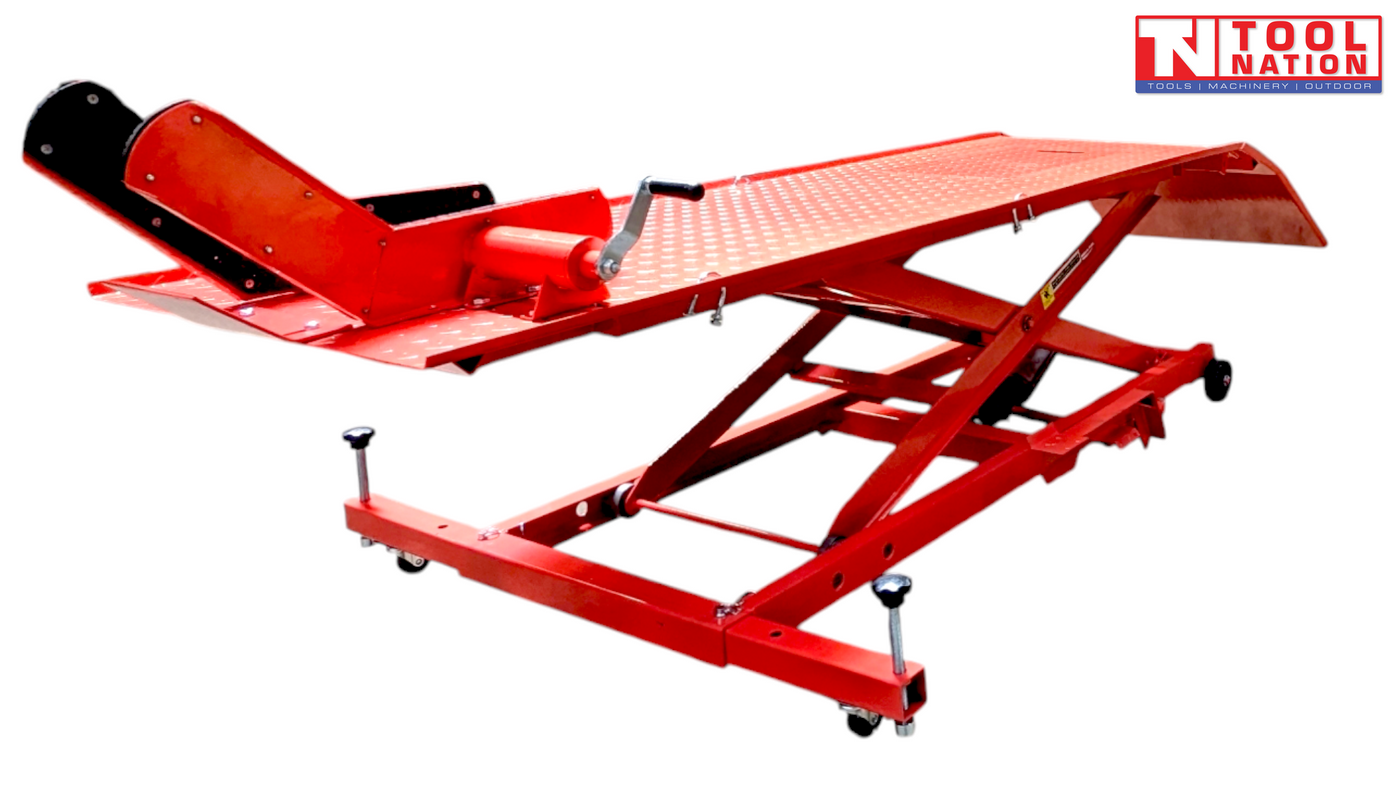 Angled front-side view of a red motorcycle lift with the rear loading ramp down, front wheel chock raised, and scissor frame partially lifted.