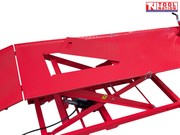Close-up of the red lift platform showing the removable center service panel opening and part of the red scissor frame underneath.