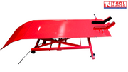 Side view of the red motorcycle lift with the loading ramp down, long platform, center service panel, front wheel chock, and air hose.
