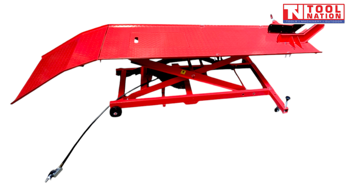 Side view of the raised red motorcycle lift with the loading ramp down, long platform, center service panel, front wheel chock, and air hose.