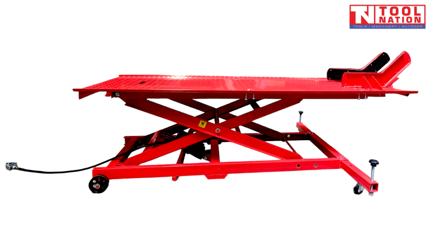 Side view of a red air hydraulic motorcycle lift raised off the ground, showing the long platform, scissor frame, wheel chock, and air hose.