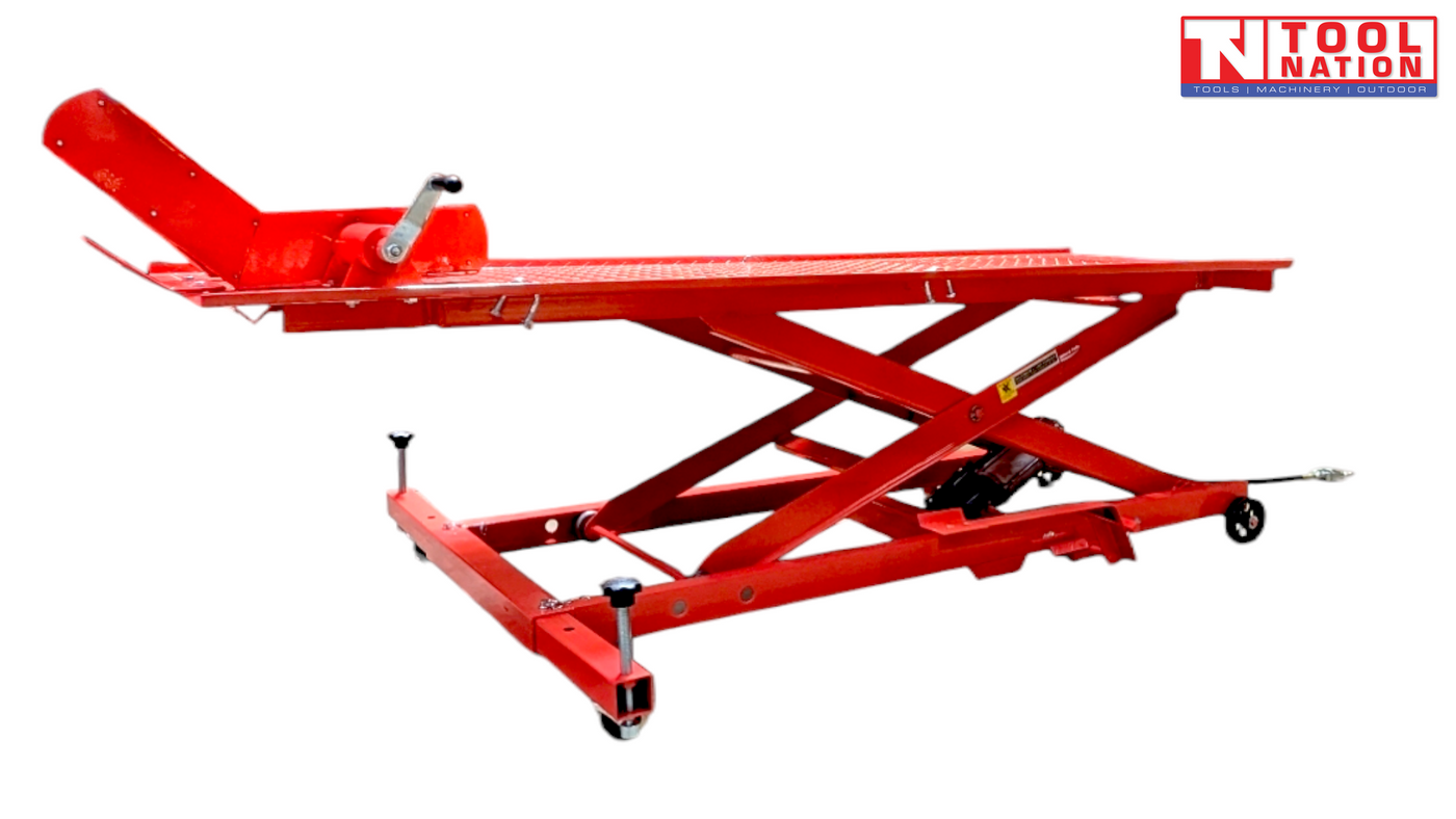 Angled side view of a red motorcycle lift with the rear loading ramp down, front wheel chock raised, and scissor frame partially lifted.