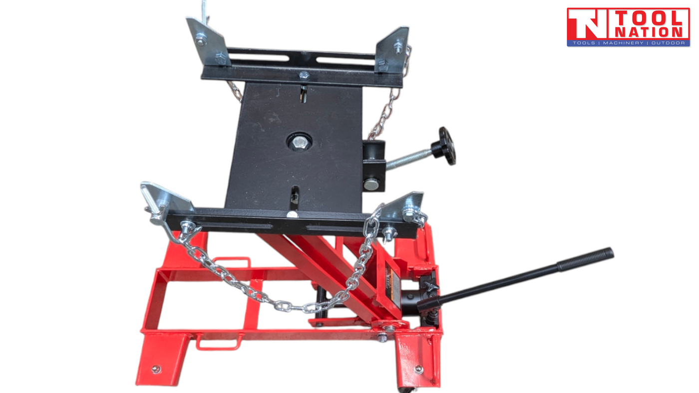 Front angled view of red hydraulic floor transmission jack with black saddle plate, safety chains, and handle
