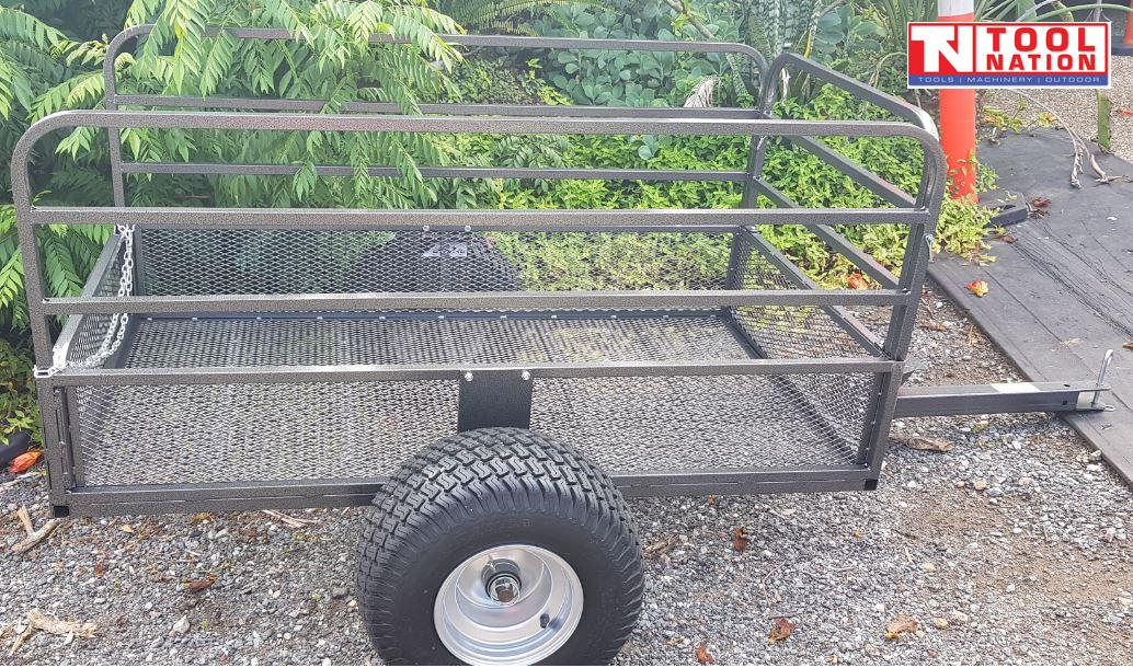 Black mesh-sided trailer shown outdoors with a long drawbar, side rails, chain, one visible tyre and Tool Nation logo.