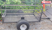 Black mesh-sided trailer shown outdoors with a long drawbar, side rails, chain, one visible tyre and Tool Nation logo.