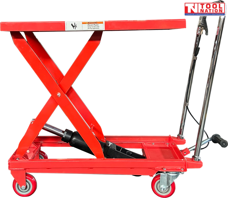 Red hydraulic lift table cart with raised scissor frame, handle, wheels, and warning label.