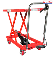 Angled view of a red hydraulic lift table cart with raised scissor frame, handle, wheels, foot pedal, and labels.