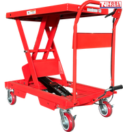 Angled view of a red hydraulic lift table cart with raised scissor frame, handle, wheels, foot pedal, and warning labels.