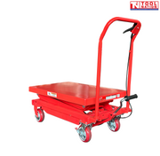 Red hydraulic lift table cart with lowered platform, handle, wheels, foot pedal, labels, and logo in the top corner.