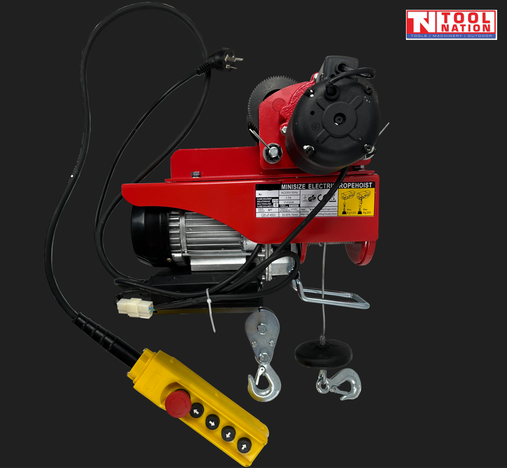 Red electric hoist with trolley wheels, hooks, power cord, and yellow pendant control on a dark background.